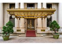 Grand building entrance with gold awning, columns, red carpet, and potted trees at 75 Ponce De Leon Ne Ave # 1006, Atlanta, GA 30308
