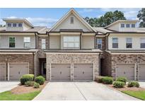 Charming townhome with brick and stone accents, a two-car garage, and well-maintained landscaping at 5590 Bright Cross Way, Suwanee, GA 30024