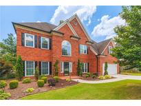 Charming two-story red brick home featuring black shutters, a well-manicured lawn, and a two-car garage at 1219 Hadaway Ct, Lawrenceville, GA 30043