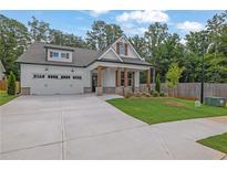 Charming two-story home featuring a manicured lawn, craftsman architecture, and a two-car garage at 153 Alaina Rd, Holly Springs, GA 30115