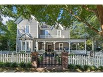 Charming two-story home featuring a covered front porch and a white picket fence at 207 E Hightower E Trl, Social Circle, GA 30025