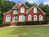 Charming two-story brick home with a well-manicured lawn and lush landscaping at 3008 Sunrise Ct, Conyers, GA 30094
