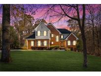 Charming two-story brick home with lush lawn, mature trees and colorful sunset sky at 340 Antebellum Way, Fayetteville, GA 30215