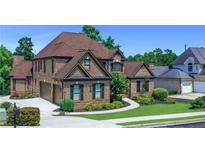 Beautiful two-story brick home featuring a manicured lawn, mature trees, and attached two-car garage at 3905 Greenside Ct, Dacula, GA 30019