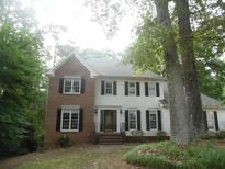 Traditional home featuring a brick facade, white siding, and manicured landscaping surrounded by mature trees at 1205 Pebble Bend Dr, Grayson, GA 30017
