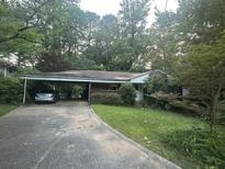 Cozy single-story home with a covered carport and a front yard surrounded by mature trees and greenery at 1164 Rogeretta Ne Dr, Atlanta, GA 30329