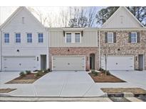 Charming townhomes showcasing brick and siding exteriors, each with a one-car garage at 693 Sunstone Ln, Lawrenceville, GA 30043