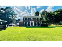 Charming brick home featuring a manicured lawn, mature trees, and classic architectural details at 1391 Warrenton Hunt, Lawrenceville, GA 30043