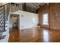 Spacious living room with hardwood floors, exposed brick wall and staircase to the loft at 1596 Cleveland Ave # 301, East Point, GA 30344