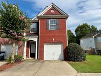 Charming brick townhome featuring a one-car garage and beautifully manicured landscaping at 3884 Grovemont Pl, Duluth, GA 30096