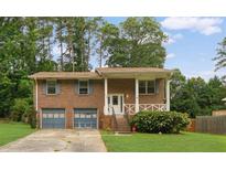 Charming brick home featuring a covered front porch, an attached two-car garage, and a well-manicured lawn at 115 Elizabeth Way, Ellenwood, GA 30294
