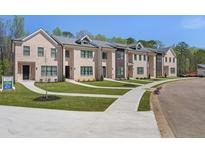 Attractive brick-faced townhomes with well-maintained lawns and sidewalks leading to covered front door entrances at 161 Brush Creek Ct, Stockbridge, GA 30281