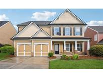 Charming two-story home with a two-car garage, a covered porch and manicured lawn and landscaping at 2040 Village Green Dr, Fairburn, GA 30213