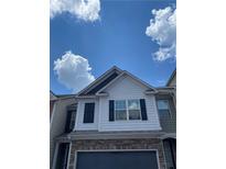 Stylish two-story home featuring stone accents, black shutters, and a gray garage door, all under a beautiful blue sky at 5715 Radford Loop # 15, Fairburn, GA 30213