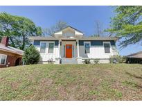 Charming home featuring blue and white exterior, a bright orange door, and a well-manicured front lawn at 1497 Rogers Ave, Atlanta, GA 30310