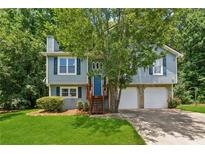 Charming two-story home featuring a blue exterior, landscaped yard, and two-car garage at 3450 Saddleton Way, Douglasville, GA 30134