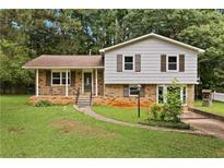 Charming split-level home featuring a brick facade, covered porch, and well-maintained lawn at 135 Buckhurst Way, Atlanta, GA 30349