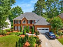 Traditional two-story brick home with a manicured lawn, mature trees, and an attached two-car garage at 1490 Rivershyre Pkwy, Lawrenceville, GA 30043