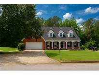 Charming two-story brick home featuring a manicured lawn, dormer windows, and a spacious two-car garage at 1945 Kevin Se Dr, Conyers, GA 30013