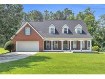 Charming brick home featuring a well-manicured lawn and inviting front porch with columns at 1945 Kevin Se Dr, Conyers, GA 30013