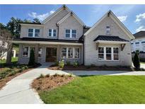 Beautiful two-story brick home with well-manicured lawn, covered front porch, and professionally landscaped yard at 2455 Bleckley Pl, Cumming, GA 30041