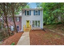 Charming home with light grey brick, blue shutters, a bright yellow door and mature trees at 2780 Northwood Court Sw Ct, Marietta, GA 30060