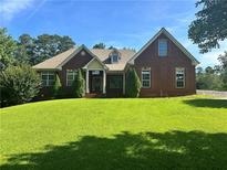 Charming single-story red brick home featuring a well-manicured lawn, lush landscaping, and a welcoming front entrance at 20 Wood Lawn Springs Trl, Covington, GA 30014