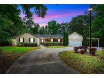 Charming single-story home with lush landscaping, a curved driveway, and a two-car garage and car port at 280 W Knight W Rd, Mcdonough, GA 30252