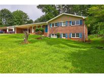 Charming brick home featuring a lush green lawn, covered parking, and inviting curb appeal at 5739 Cobb Mdw, Norcross, GA 30093