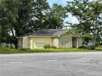 Quaint one-story home with a gable roof, lattice facade, and surrounded by mature trees on an overgrown lot at 1891 Bennett Rd, Grayson, GA 30017