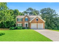 Beautiful two-story brick home with a well-manicured lawn and a two-car garage at 7505 Brookwood Way, Cumming, GA 30041