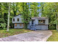 Charming gray two-story home with stone accents, a covered entryway, and a winding driveway surrounded by lush trees at 3442 Winter Wood Trl, Marietta, GA 30062