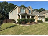 Charming two-story home boasts a well-manicured lawn and inviting curb appeal with manicured shrubbery at 2380 Cain Cir, Dacula, GA 30019