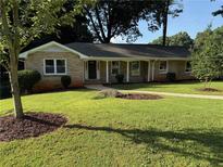 Charming brick home featuring a well-manicured lawn, inviting front porch, and mature trees at 2545 Glenrock Dr, Decatur, GA 30032