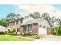Charming two-story brick home with manicured lawn and an attached garage, offering great curb appeal at 830 Montego Sw Way, Lilburn, GA 30047