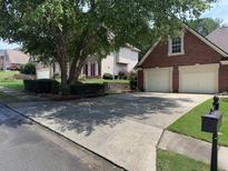 Traditional brick home with a two-car garage and a well-maintained lawn and a shade tree at 805 River Valley Dr, Dacula, GA 30019