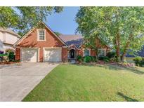 Charming brick home featuring a well-manicured lawn, mature trees and a three car garage at 805 River Valley Dr, Dacula, GA 30019
