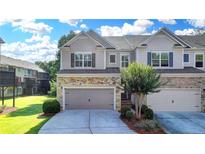 Beautiful townhome featuring a stone and gray siding facade with a well-maintained lawn and a two-car garage at 5965 Vista Brook Dr, Suwanee, GA 30024