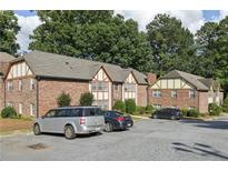 Brick apartment building with a parking lot, green trees, and a well-maintained lawn at 2825 Northeast Ne Expy # F003, Atlanta, GA 30345