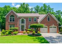Beautiful brick home with a well-manicured lawn and mature trees at 545 Ashvale Overlook, Alpharetta, GA 30005