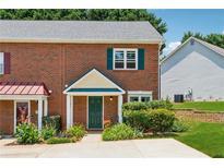 Charming brick townhome with a well-manicured front yard and inviting green front door at 3665 Magnolia Walk Trl, Cumming, GA 30040