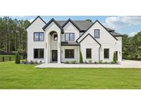 Stunning two-story home featuring a painted brick exterior, dark trim, arched entryway, and manicured lawn at 3205 Bold Springs Rd, Dacula, GA 30019