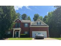 Charming two-story brick home featuring a two-car garage, manicured lawn, and classic architectural details at 6432 Polar Fox Ct, Riverdale, GA 30296