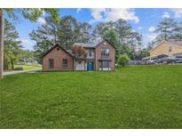 Charming brick two-story home boasts a manicured lawn and a bright blue front door at 4000 Brittan Glade Trl, Snellville, GA 30039