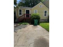 Cozy yellow home featuring a quaint entrance deck and a concrete driveway leading up to the stairs at 3490 Kingswood Trl, Decatur, GA 30034