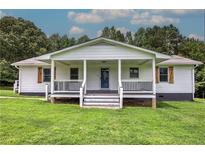 Charming home featuring a covered porch with stylish railings and lush green lawn at 2122 Browntown Rd, Rockmart, GA 30153