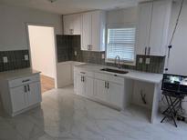 Bright kitchen featuring white cabinets, modern countertops, gray backsplash, and stylish tile flooring at 5400 Louis Xiv Ln, Atlanta, GA 30349
