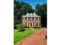 Charming two-story brick home with black shutters, dormer windows, manicured lawn, and brick driveway at 3201 Palisades Se Ct, Marietta, GA 30067
