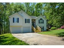 Charming two-story home with attached garage, stone accents, and landscaped front yard surrounded by mature trees at 8130 Estee Dr, Cumming, GA 30028