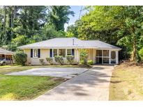 Charming single-story home with a well-manicured lawn, screened in porch and a concrete driveway at 3205 Mcafee Rd, Decatur, GA 30032